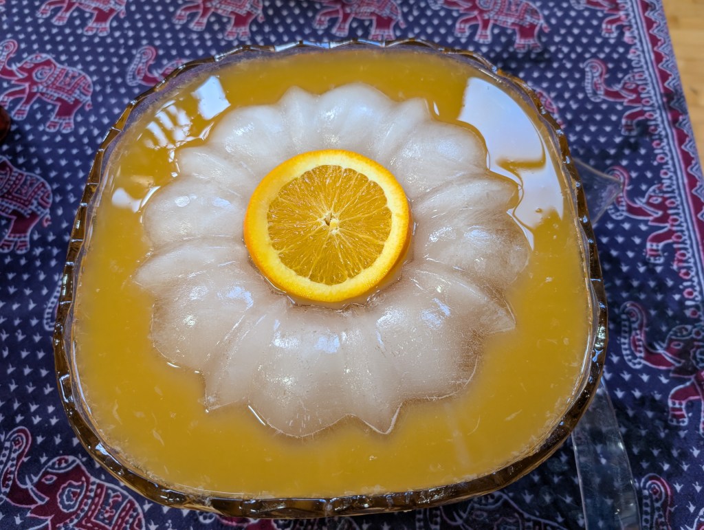 apricot mist in a small-to-medium-sized punch bowl with a Bundt-shaped ice ring and a slice of orange