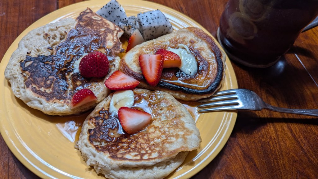 banana pancakes with maple syrup, strawberries, and dragon fruit