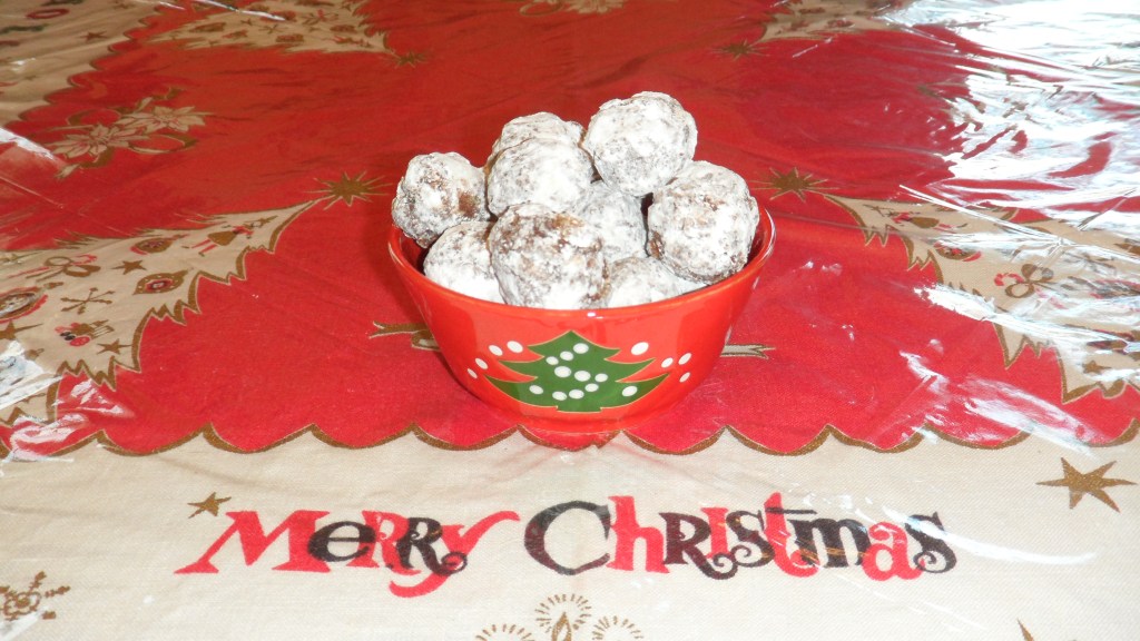 bourbon balls in a holiday bowl on a holiday tablecloth