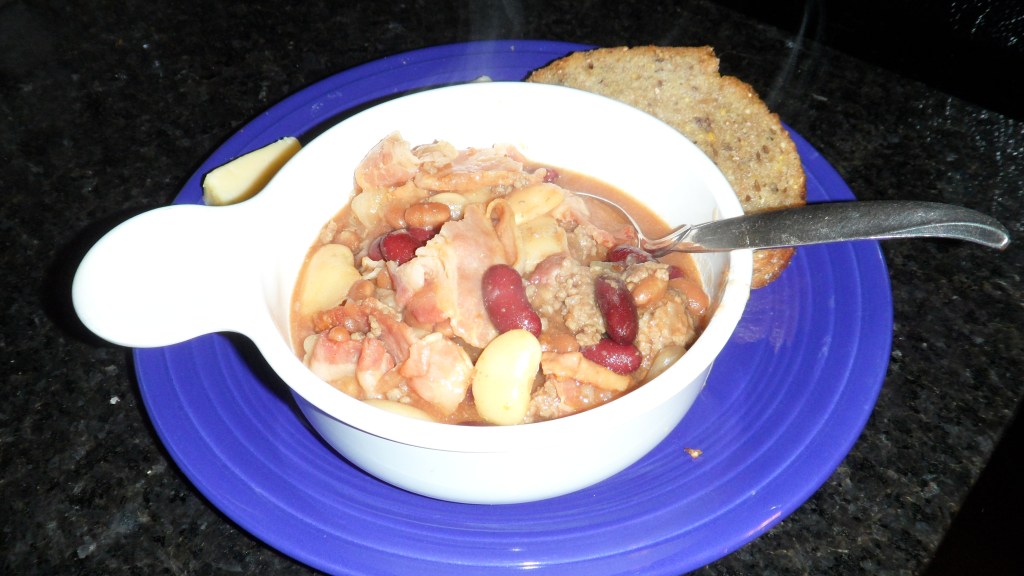 Calico beans served with a slice of nutty bread and a piece of cheese