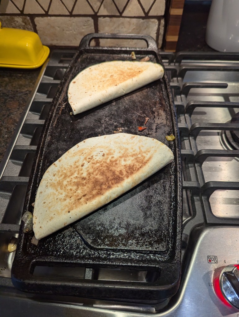 Quesedillas folded over on a griddle to finish cooking