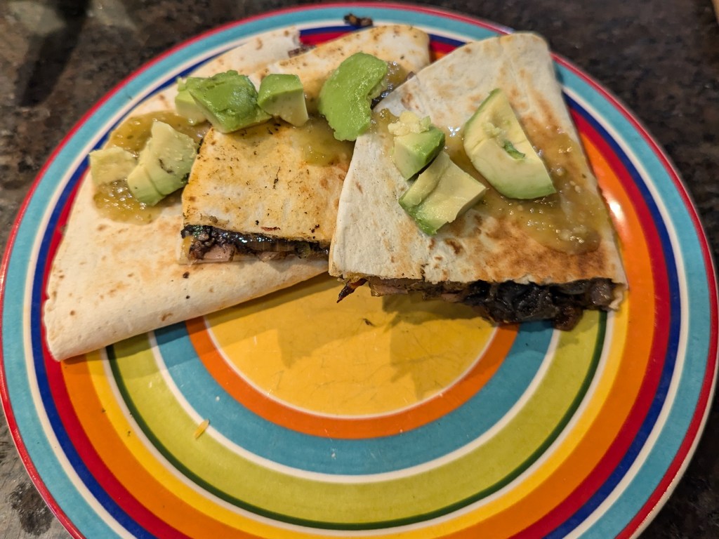 huitlacoche quesedilla sliced into 3 halves and topped with avocado slices and salsa verde