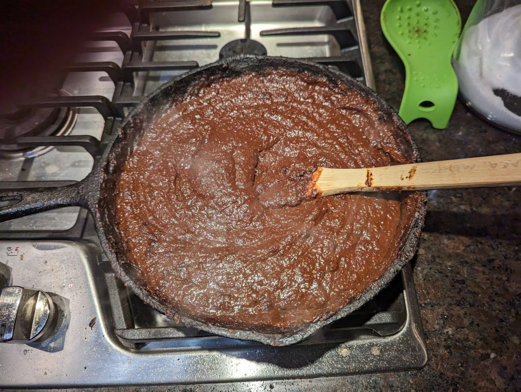 Mole negro cooking in an iron skillet