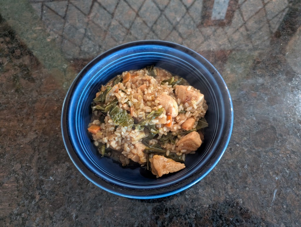 orange cinnamon rice chicken with kale and carrots in a ceramic bowl