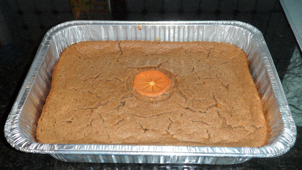 persimmon pudding in an aluminum baking dish with a slice of persimmon on the top