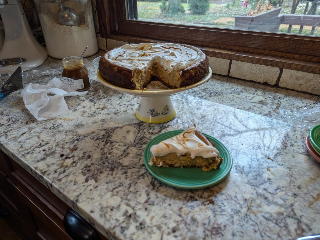 Pumpkin cheesecake on a cake platter with one slice served on a plate