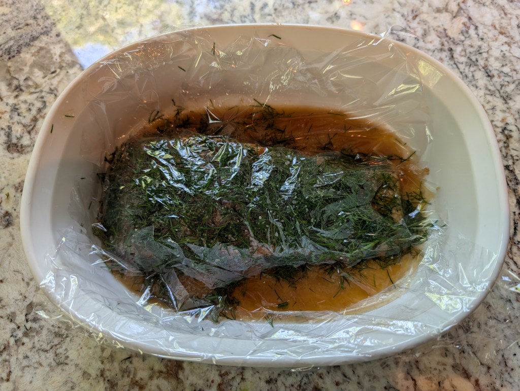 Gravlax covered with plastic wrap and ready to cure