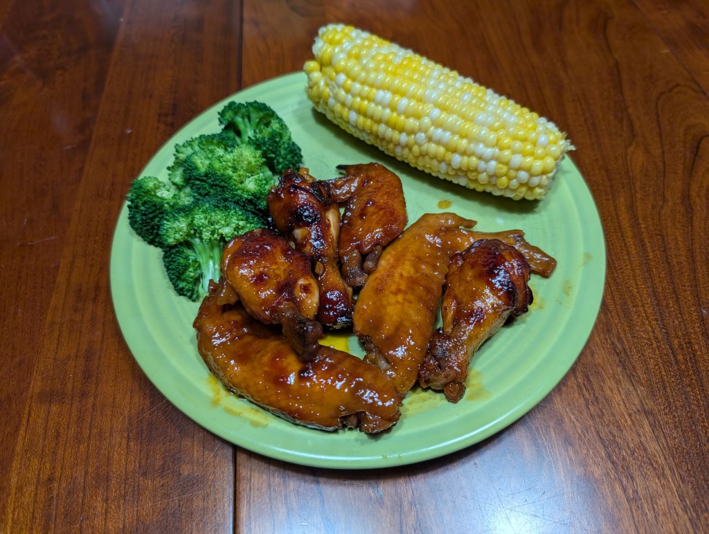 Honey chicken wings served with corn on the cob and steamed broccoli