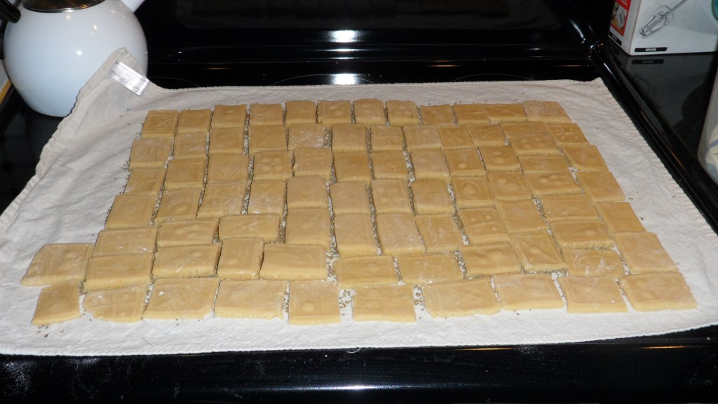 springerle cookies cut out and resting on anise seeds on a tea towel