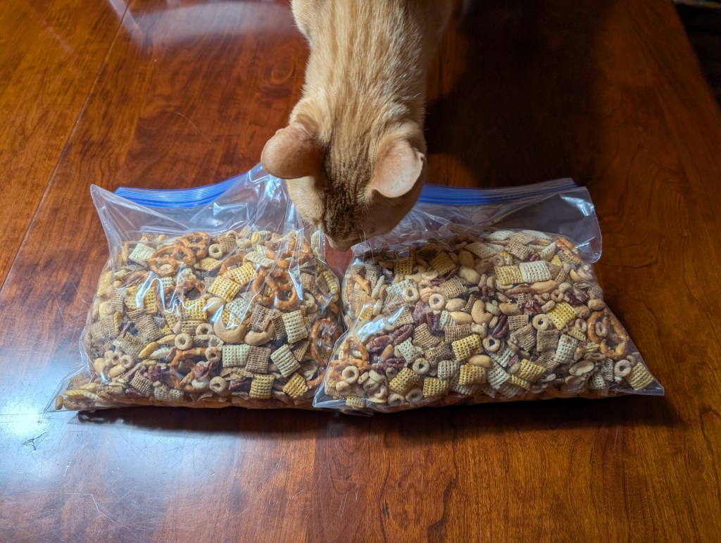 Two gallon bags of cereal mix, 2/3 full. My cat sniffs the bags.