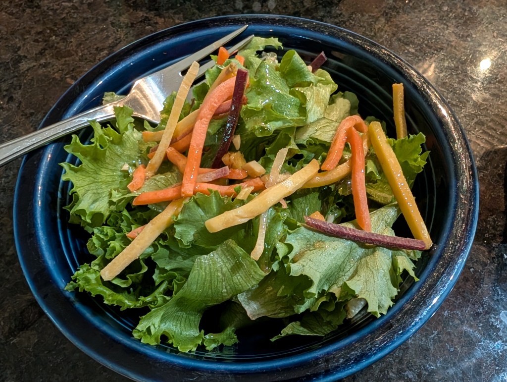 Ginger salad dressing on a bed of greens and matchstick carrots