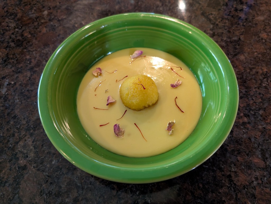 Ladoo in a tres leches sauce with saffron threads and rose petals