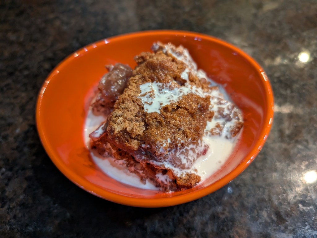 Peach cobbler in a bowl with cream