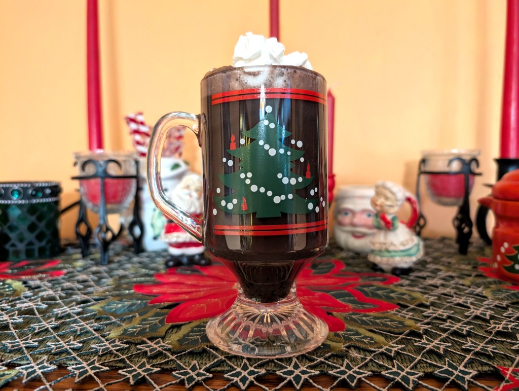 dark hot chocolate in a holiday mug with a dollop of whipped cream