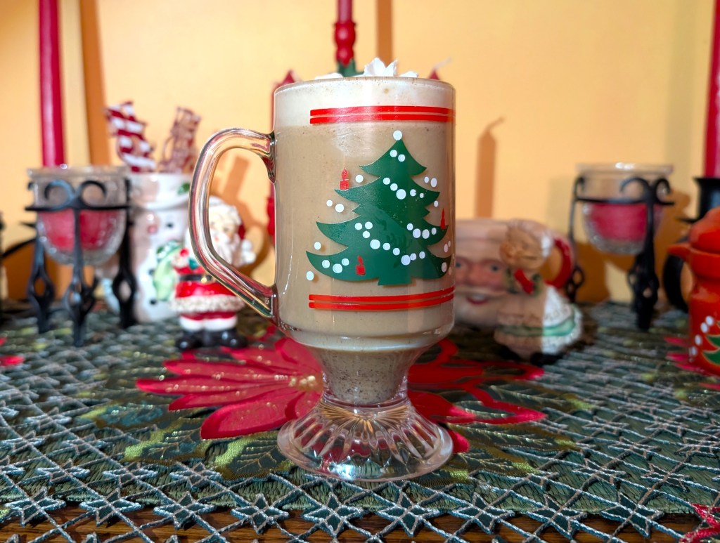 Egg nog in a holiday glass mug with a dollop of whipped cream