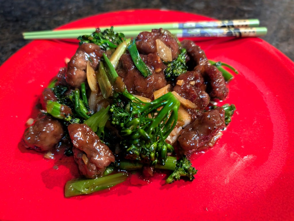 Mongolian ground beef served on a plate over steamed rice with chopsticks