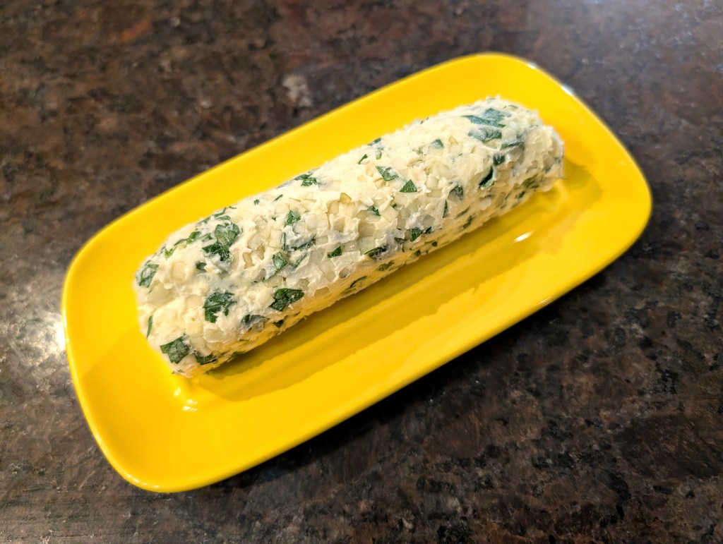 Garlic herb butter formed into a tube and served on a butter dish