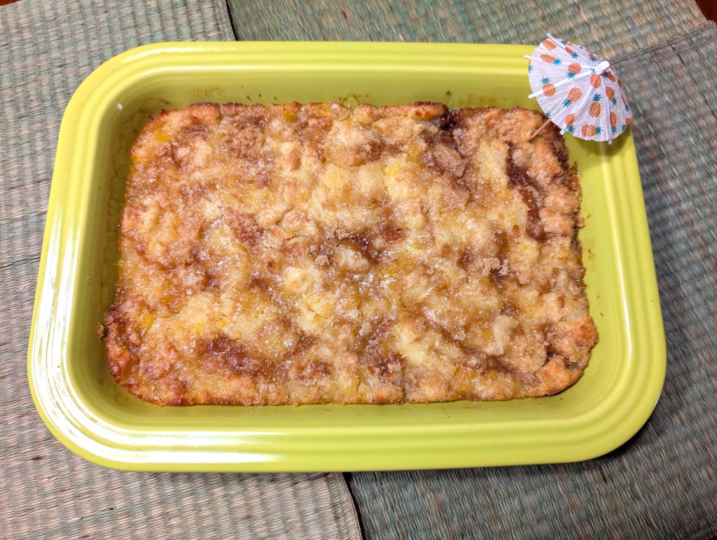scalloped pineapple in a casserole dish with a paper umbrella because why not